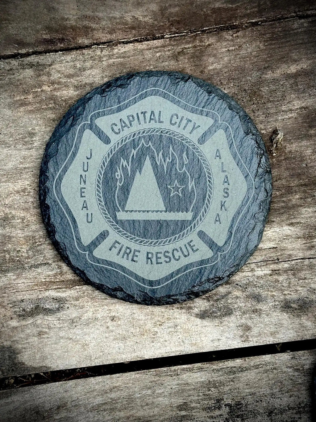 Round slate coaster with 'Capital City Fire Rescue' logo on a wooden surface