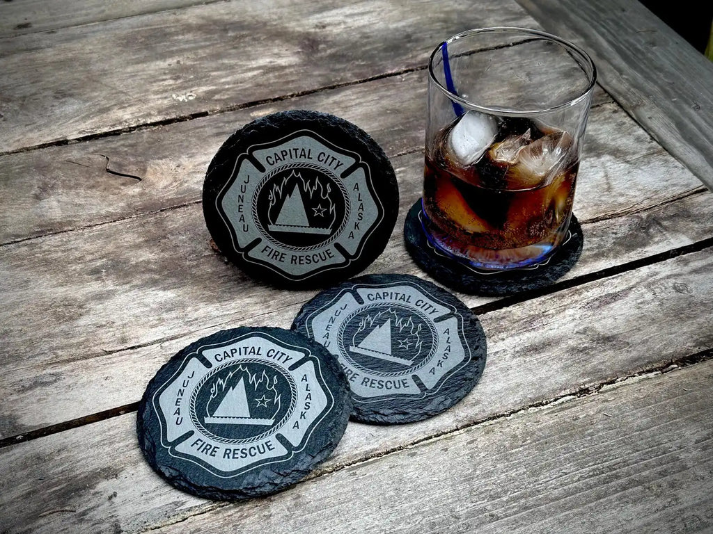 Coasters with 'Capital City Fire Rescue' logo on a wooden surface with a glass of iced drink.