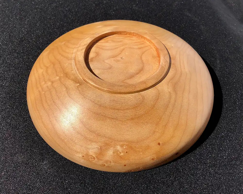 Wooden bowl with a central circular depression on a black background