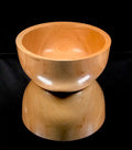 Wooden stool with a bowl-like top on a black background