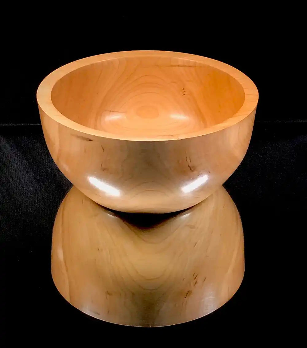Wooden stool with a bowl-like top on a black background
