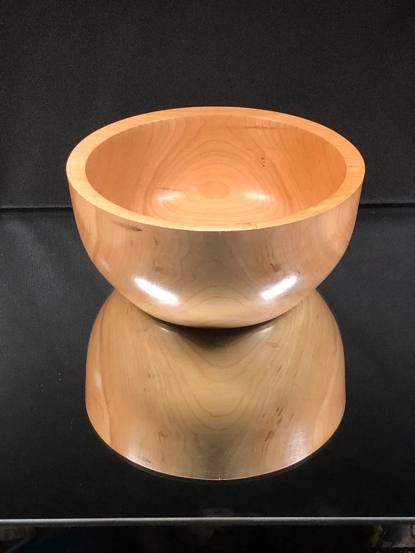 Wooden bowl on a black reflective surface with a dark background
