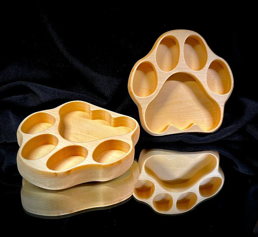 Two wooden paw-shaped trays on a black background