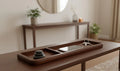 Wooden tray with phone, keys, and stones on a wooden surface in a room.